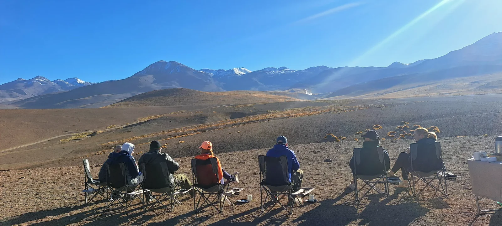 Viajeros sentados juntos frente al paisaje de Atacama durante una parada del recorrido