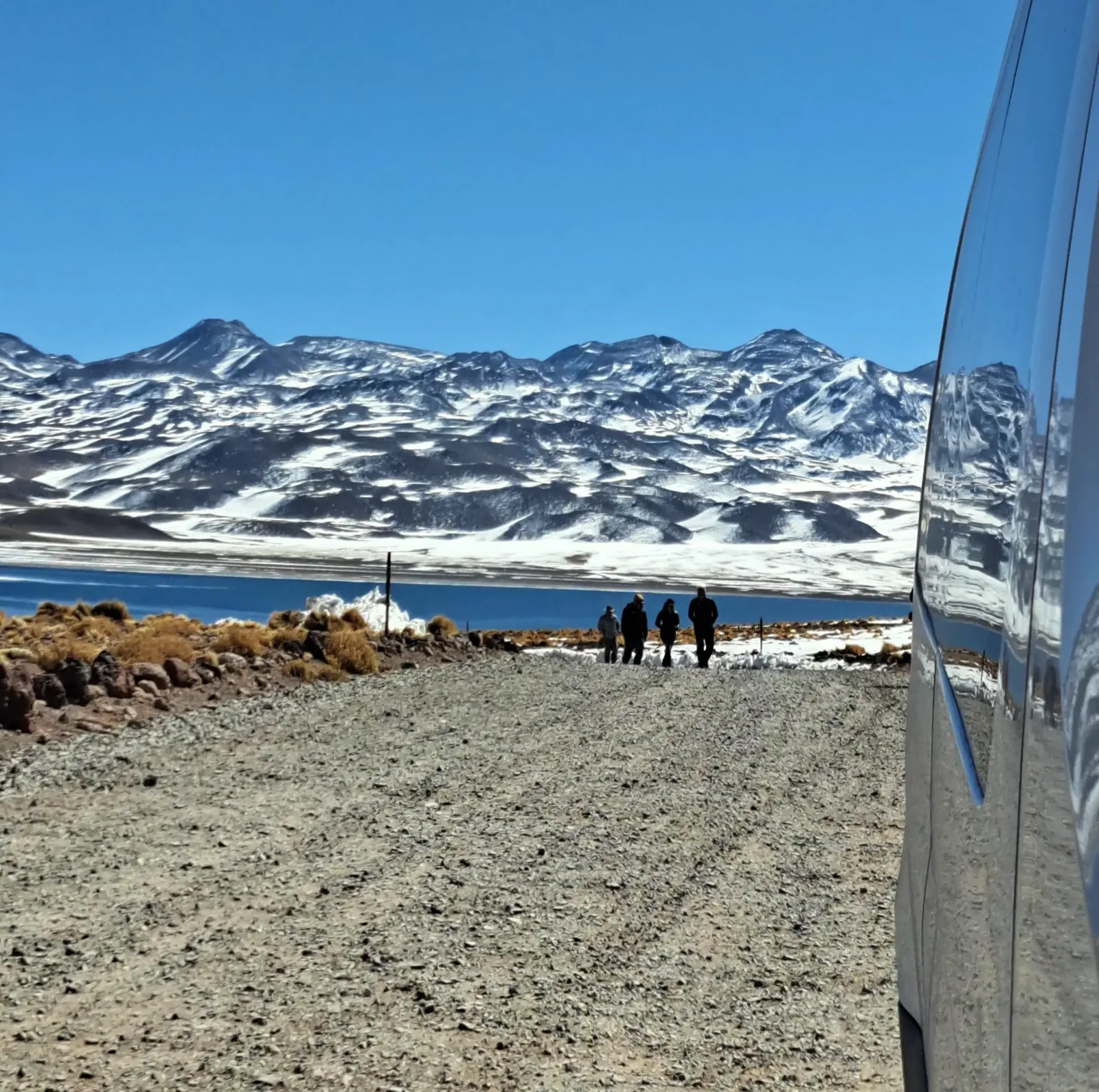 Viajeros y vehículo junto a una laguna del altiplano durante una jornada compartida