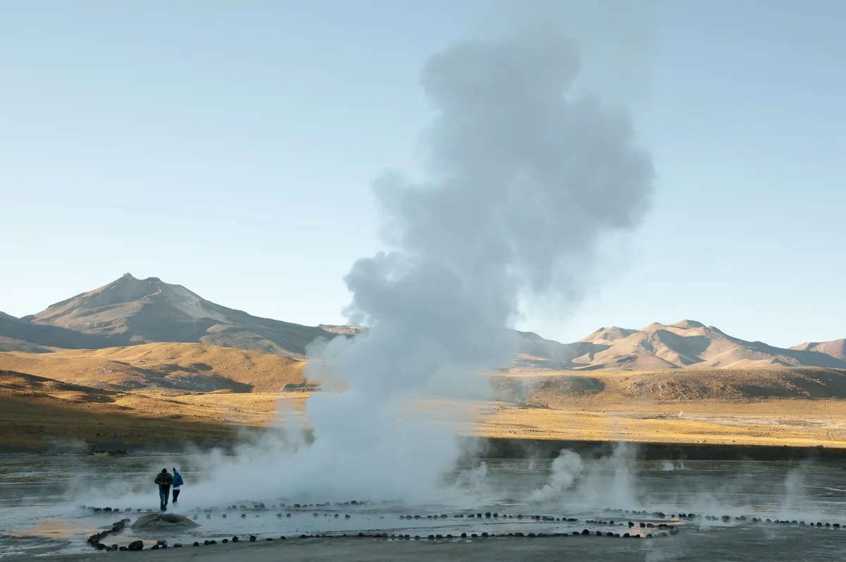 Viajeros entre columnas de vapor en los géiseres del Tatio al amanecer